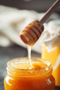 Honey background. Sweet honey in glass jar on wooden background. Close up.